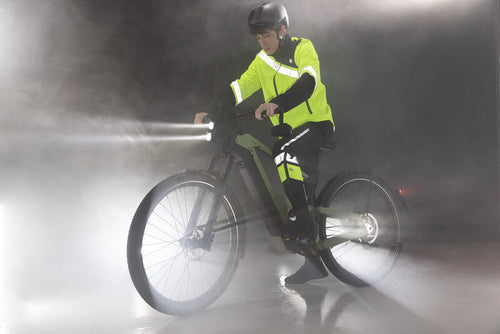 Cycliste éclairé et réfléchissant à vélo dans la pluie et le brouillard de nuit