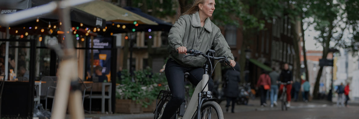 Cycliste à vélo de ville dans une rue commerçante, antivols et éclairages AXA