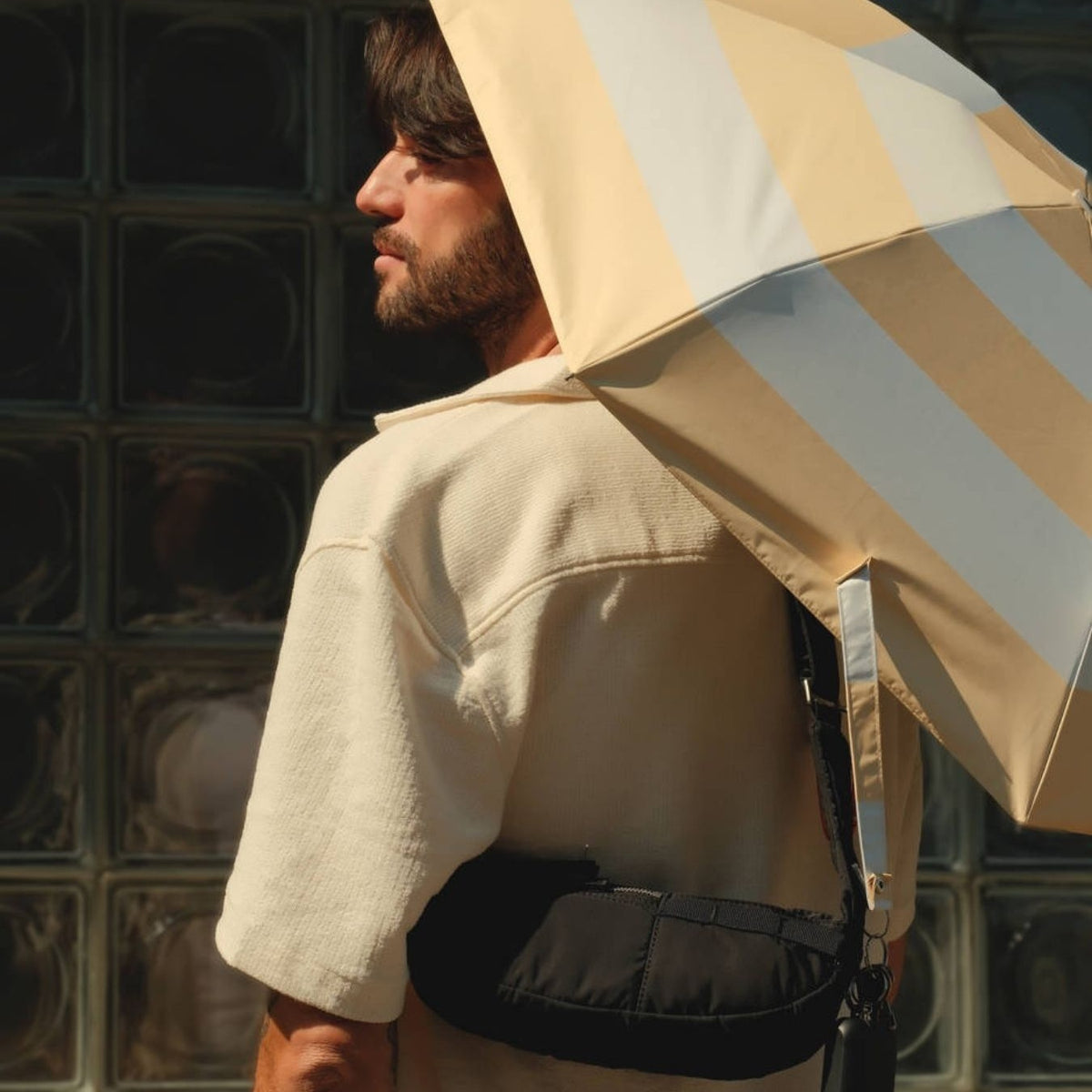 Parapluie-ombrelle Anatole rayures jaune lin porté sur l'épaule en ville