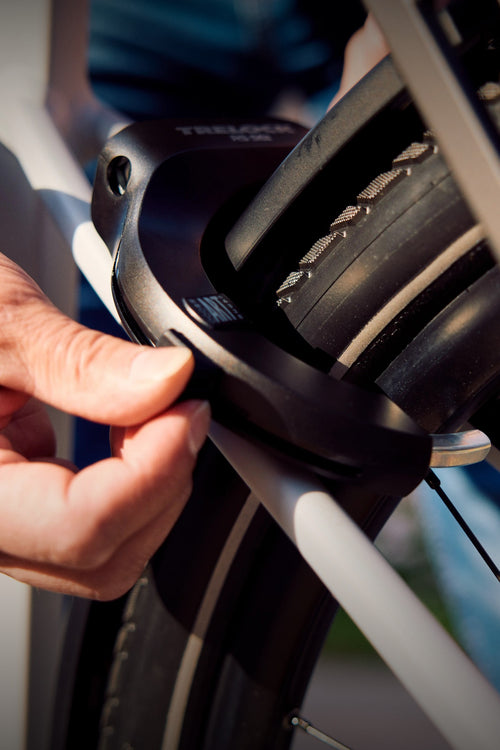 Antivol de cadre Trelock RS 561 verrouillé à la main sur la roue arrière d'un vélo de ville