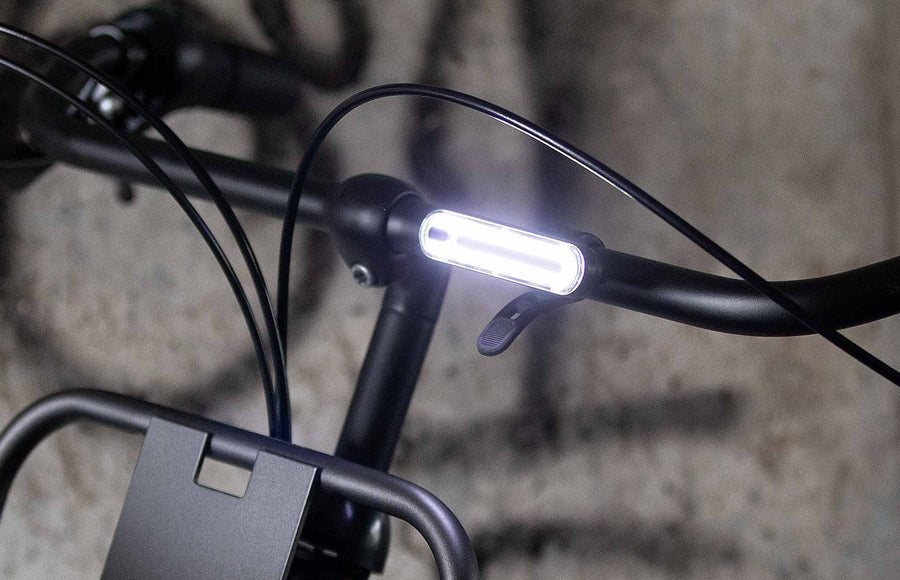 Éclairage avant Urban Proof LED 200 lm allumé sur un guidon