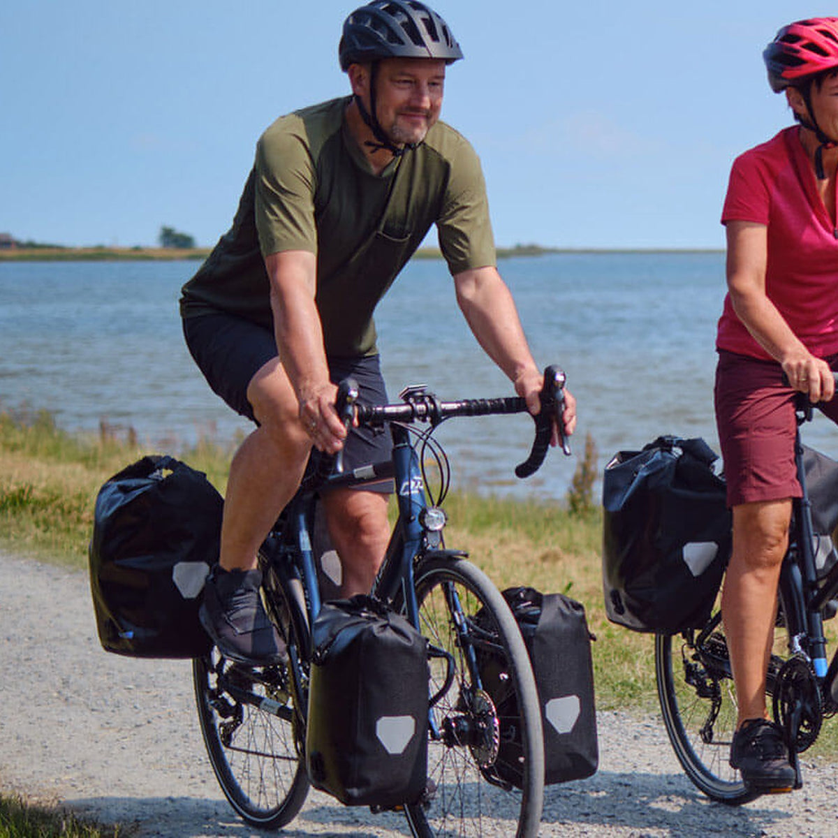 Couple de cyclistes équipés SIGMA roulant au bord de la mer
