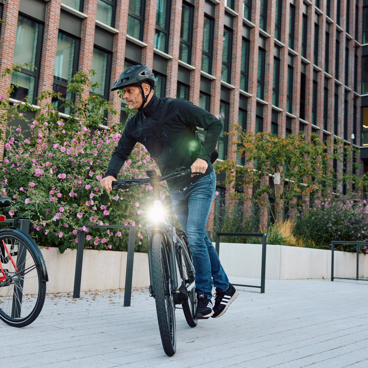 Cycliste partant à vélo électrique d'un parking vélo urbain, histoire de Trelock